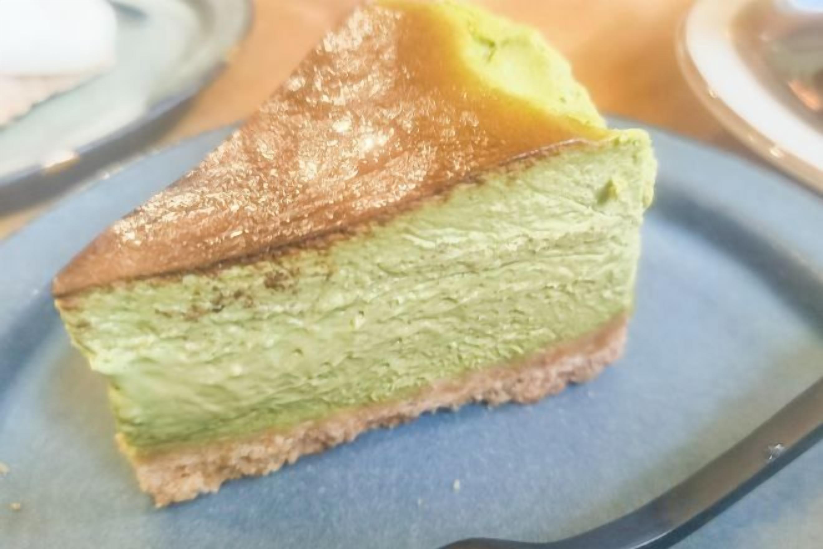 A slice of cake with a golden top and green filling on a blue plate.