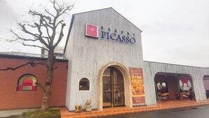 A building with a sign reading 'BAKERY PICASSO' and a large arched entrance. - Sakura (Nagoya)