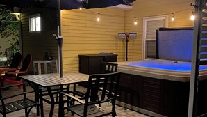 An outdoor deck with a hot tub, a table with chairs, and string lights. - Cozy Gem, Hot Tub,  close to downtown Berkley shops and restaurants (Berkley)