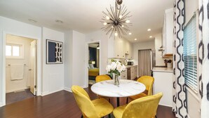 A dining area with a round table and yellow chairs, a modern chandelier, and a view into the kitchen. - Cozy Gem, Hot Tub,  close to downtown Berkley shops and restaurants (Berkley)