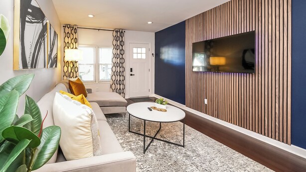 A modern living room with a sofa, coffee table, and a TV mounted on a wooden wall. - Cozy Gem, Hot Tub,  close to downtown Berkley shops and restaurants (Berkley)