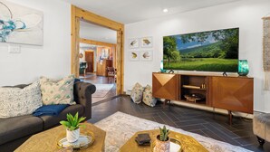 Un salon moderne avec un canapé, une table basse et un téléviseur. On y trouve également un meuble en bois et un tableau accroché au mur.