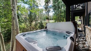 Un jacuzzi al aire libre con vistas a árboles y un edificio en el fondo.