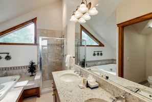 Une salle de bain moderne avec un grand miroir, deux lavabos, une douche et une baignoire.