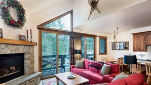 Una sala acogedora con chimenea, un sofá rojo y un amplio ventanal con vistas a una terraza.