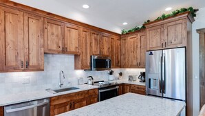 Una cocina moderna con armarios de madera, electrodomésticos de acero inoxidable y encimera de granito.