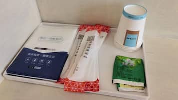 A tray with a white cup, a blue booklet, and two packets of tea.