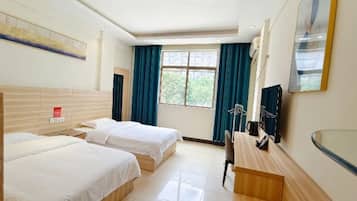 Habitación de hotel con dos camas, un escritorio, una silla, un televisor y una ventana con cortinas.