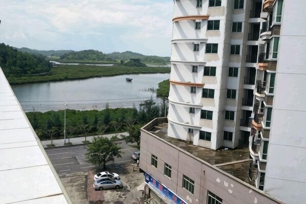 A multi-story building with a view of a river and greenery. - Xinxin Business Hotel (Qinzhougang Plaza Branch) (Qinzhou)