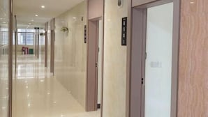 Un pasillo moderno de hotel con piso pulido, puertas de madera y placas con números de habitaciones.
