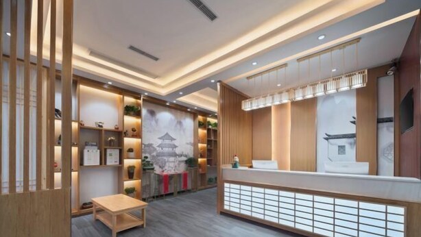 A reception area with a wooden reception desk, a waiting area with a table, and a wall with a traditional Japanese painting. - Chenyue Hotel (Chengdu Southwest University of Finance and Economics Subway Station) (Chengdu)