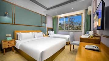Una habitación de hotel con una cama grande, dos mesitas de noche, un escritorio con una silla, un ventanal con vistas y un televisor de pantalla plana.