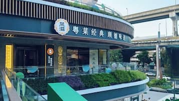 Un edificio moderno con fachada curva, señalización que indica que es un restaurante y un jardín en la azotea.