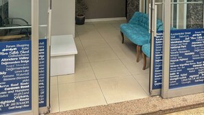 The entrance to the Kalmuk Suite Hotel with a reception area, a seating area with a blue chair, and a sign listing nearby attractions. - Kalmuk Suite Hotel (Trabzon)