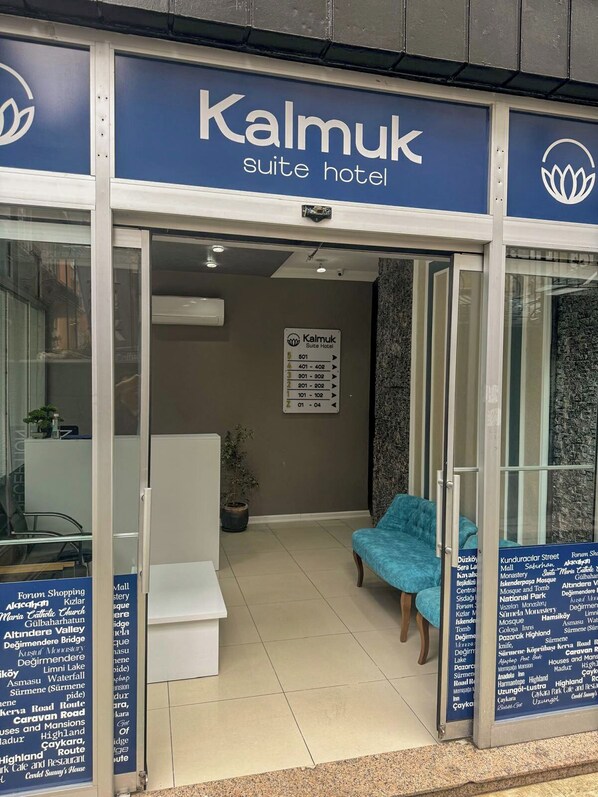 L’entrée de l’hôtel Kalmuk Suite comprend un espace d’accueil, un coin salon avec un fauteuil bleu et un panneau indiquant les attractions situées à proximité.