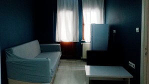 A small, dimly lit room with a blue wall, a white radiator, a blue sofa, and a small table. - Kalmuk Suite Hotel (Trabzon)