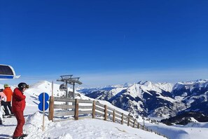 A snow-covered mountain slope with a wooden fence and a ski lift in the background.