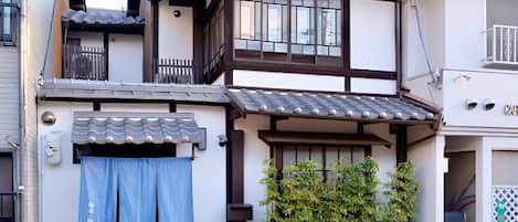 Un edificio de estilo japonés tradicional con tejado de tejas, vigas de madera y un pequeño balcón.