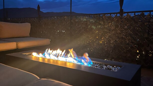 A modern outdoor seating area with a built-in fire feature, a cushioned sofa, and a decorative wall. - Entire home in Palmer Lake, CO (Palmer Lake)