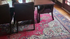 A dining room with a wooden table, chairs, a chandelier, and a large window with curtains. - Charming 1925 House in the Heart of DeLand.  (DeLand)