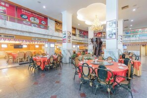 Een restaurant met meerdere eettafels, stoelen en een kroonluchter.