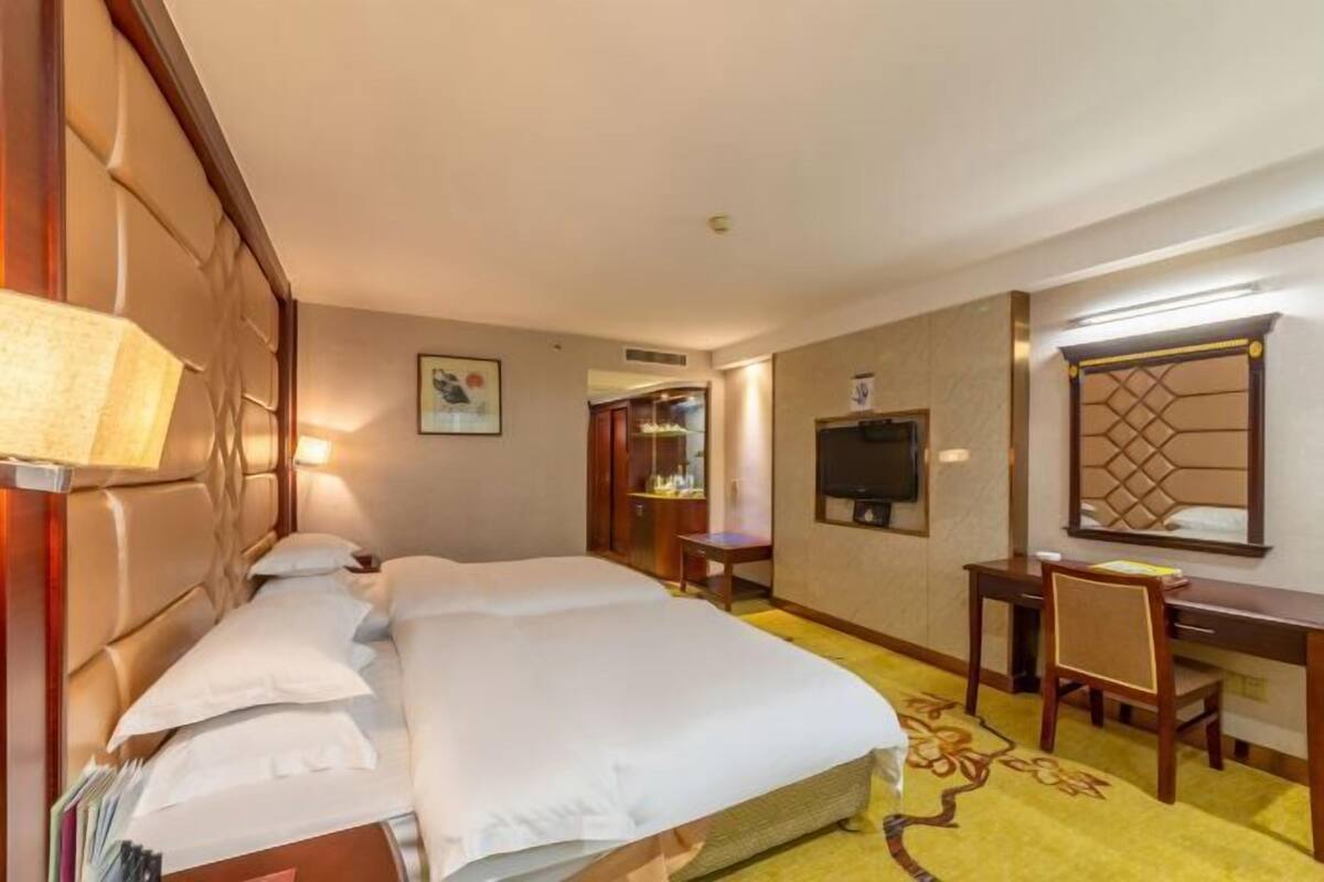 Een hotelkamer met een groot bed, een bureau, een stoel, een televisie en een spiegel.