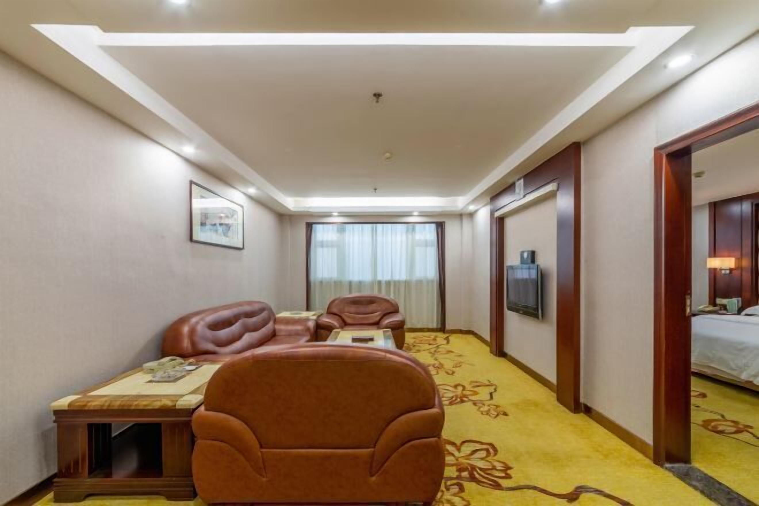 A hotel room with a sofa, a desk, a television, and a bed.