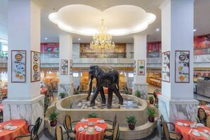 A restaurant with a central elephant sculpture, marble columns, and a chandelier. - Jin Yuan Holiday Hotel (Shantou)