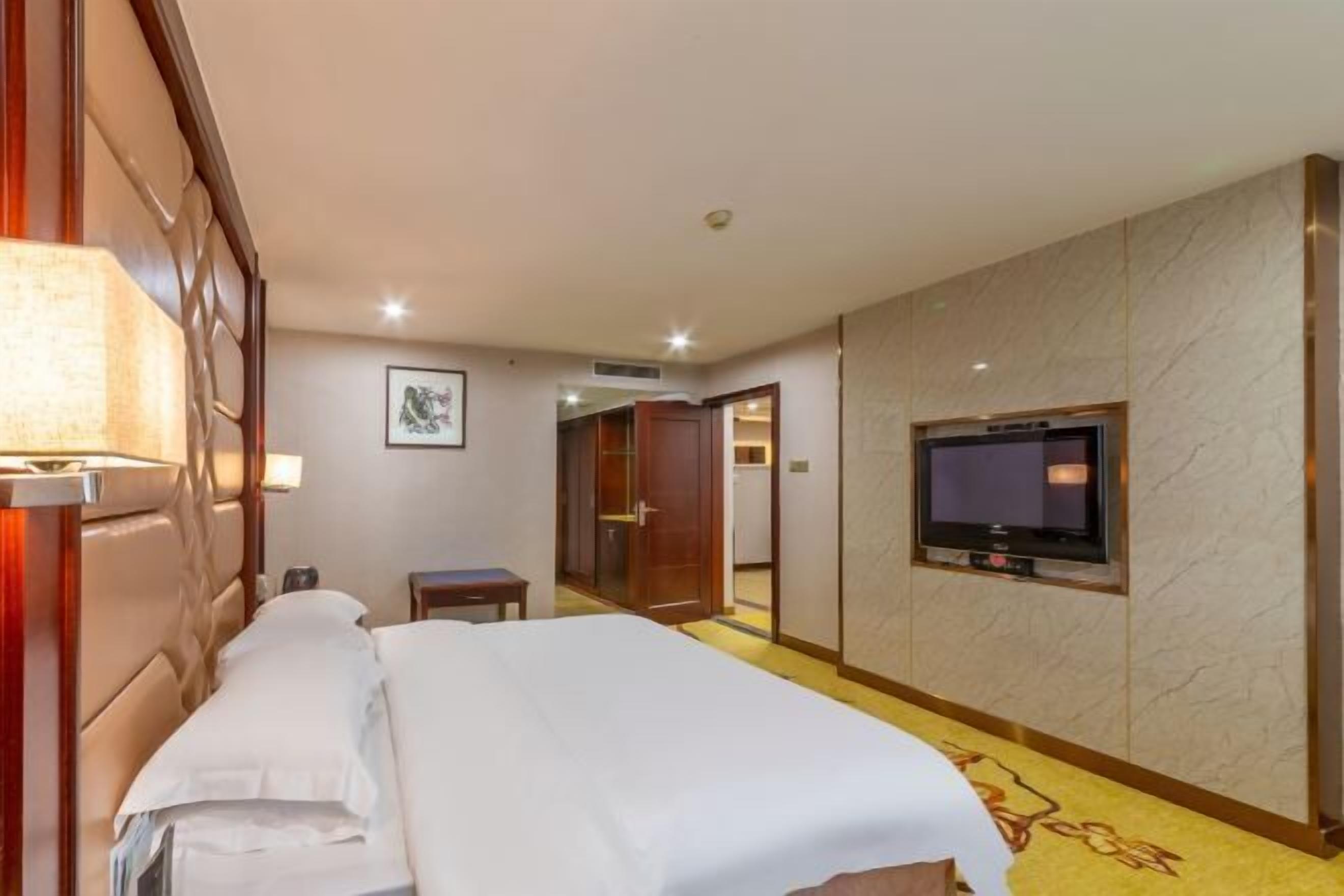 Ein Hotelzimmer mit einem Bett, einem Fernseher, einem Schreibtisch und einem Kleiderschrank.