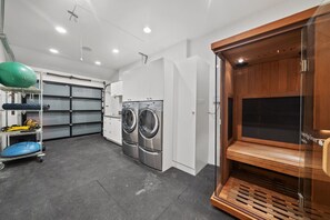 A laundry room with two washing machines, a drying rack, and a wooden cabinet.