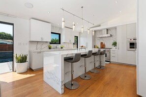 A modern kitchen with a marble island, bar stools, and stainless steel appliances.