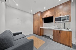 A compact kitchenette with wooden cabinets, a microwave, and a built-in oven.
