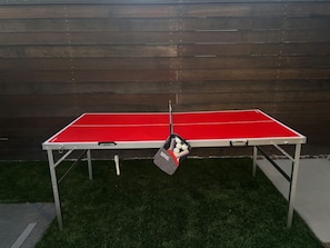 Una mesa de ping pong con una bolsa de pelotas frente a una pared de madera.