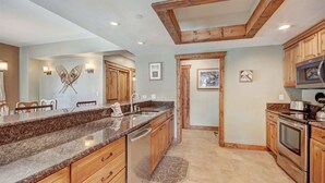 Una cocina moderna con encimeras de granito, armarios de madera y electrodomésticos de acero inoxidable.