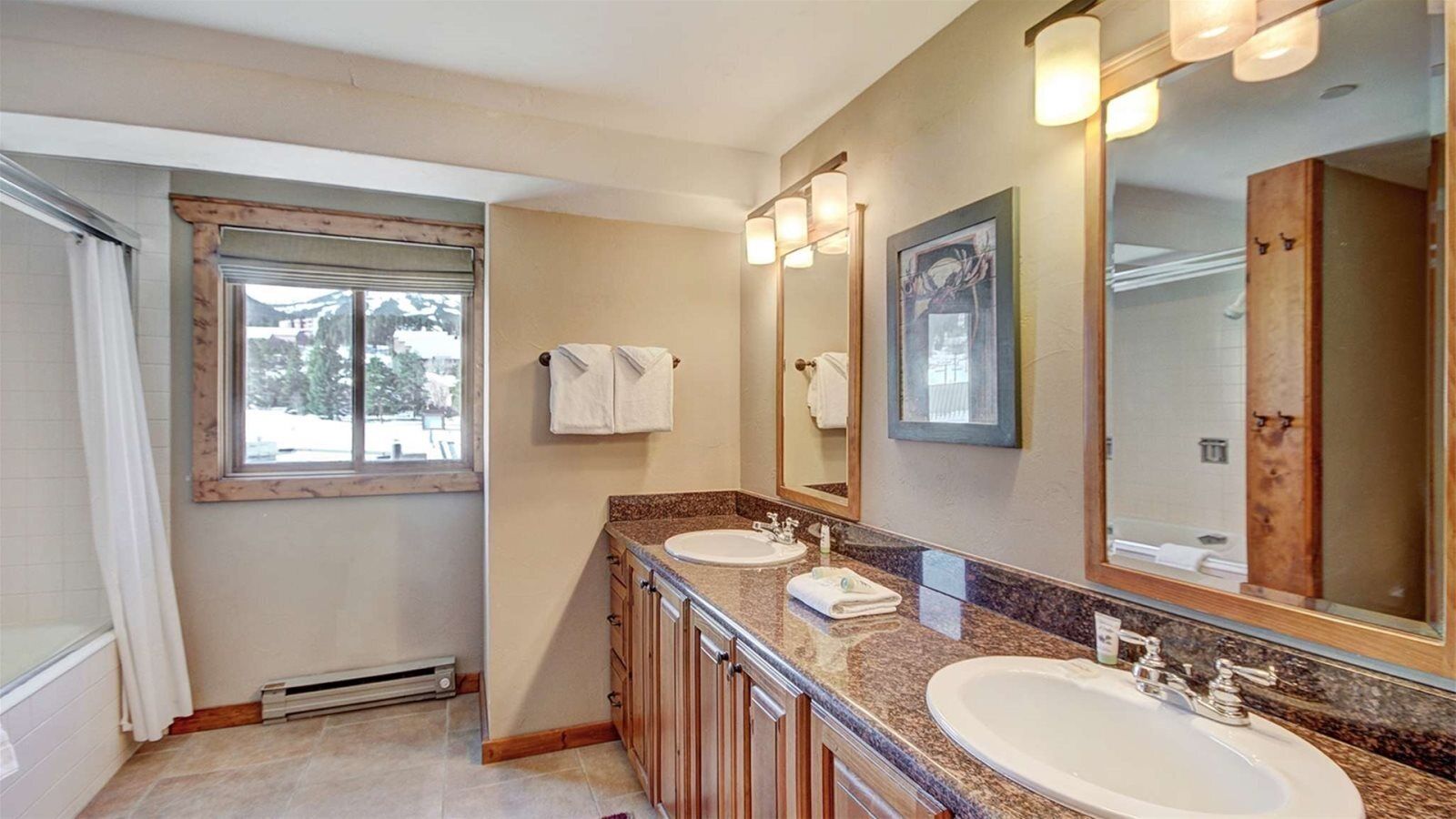 A bathroom with two sinks, a large mirror, and a window.