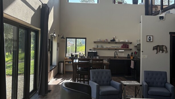 A spacious living area with large windows, a kitchen, and a dining area.