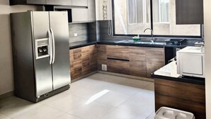 Una cocina moderna con un refrigerador de acero inoxidable, gabinetes de madera oscura, una encimera negra y una ventana con vistas.