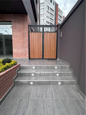 Un conjunto de escalones de piedra gris que conducen a una reja de metal negro con paneles de madera.
