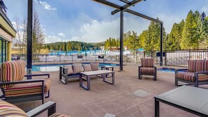 Un patio exterior con mobiliario, una piscina y vistas a un paisaje montañoso.