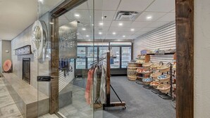 Interior moderno de un mercado con puertas de cristal, una percha de ropa y cestas de productos.