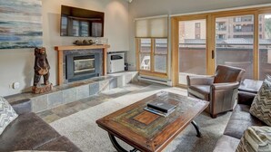 A living room with a fireplace, leather sofa, and a coffee table. - Comfortable 3-bedroom Ski In/out Condo at Peak 9 - Village at Breckenridge (Breckenridge)