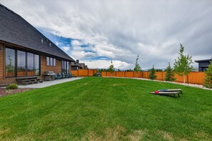 A modern house with a large lawn, a barbecue area, and a wooden fence. - New Modern 5BR with AC - Walk to Targhee Shuttle (Driggs)