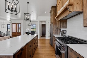 Une cuisine moderne dotée d’un grand îlot central, de meubles en bois et d’appareils électroménagers en acier inoxydable.
