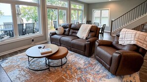 A spacious living room with a large brown leather sofa, a round coffee table, and a patterned rug. - Escape to a lakeside cabin with stunning panoramic views of Ottertail Lake
 (Ottertail)