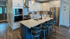 A modern kitchen with white cabinets, stainless steel appliances, and a central island with bar stools. - Escape to a lakeside cabin with stunning panoramic views of Ottertail Lake
 (Ottertail)