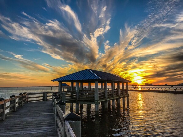 A wooden pier extending into a body of water with a gazebo structure at the end.