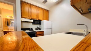 Une cuisine équipée de meubles en bois, d’un four à micro-ondes, d’une cuisinière, d’un réfrigérateur et d’un évier.