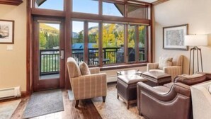 A spacious living room with large windows, a fireplace, and a cozy seating area. - Ski In, Ski Out 3 Bedroom Condo at the Eagle Bahn Gondola With Slopeside Pool (Vail)