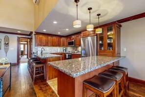 A spacious kitchen with granite countertops, wooden cabinets, and stainless steel appliances. - Ski In, Ski Out 3 Bedroom Condo at the Eagle Bahn Gondola With Slopeside Pool (Vail)