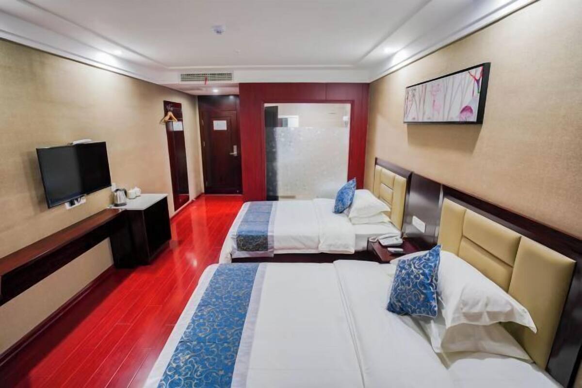 Une chambre d’hôtel avec deux lits, une télévision, un bureau et une porte.